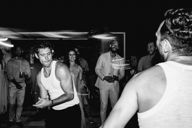 A black and white photo of guests dancing and laughing in the evening.