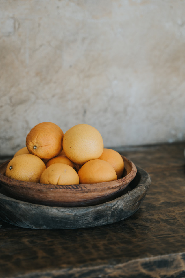 A wooden bowl of oranges on a weathered dark table at the venue.