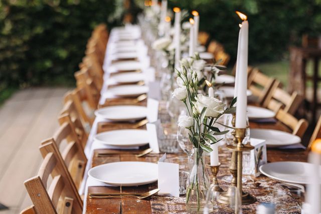 Long outdoor wedding table with candles and white flowers