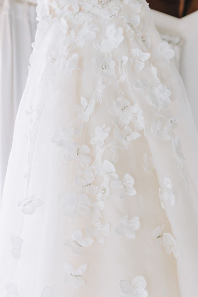 Gros plan sur une robe de mariée blanche avec des broderies florales délicates et des accessoires en perles