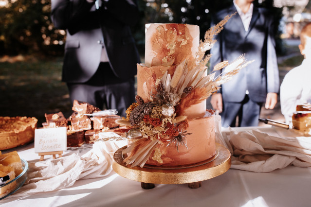 Mehrstöckige Hochzeitstorte mit Trockenblumen und orangenem Aquarelldesign