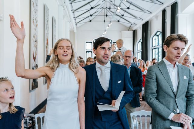The couple walks back down the aisle with raised hands as guests celebrate around them.