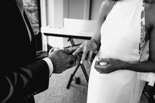 A black and white photo of the ring exchange as the couple shares the moment.
