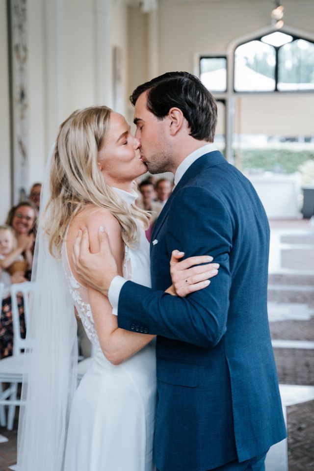 The couple shares their first kiss during the ceremony as guests watch.