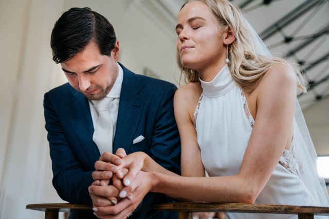 A couple hold hands with their eyes closed during an emotional moment at the ceremony.