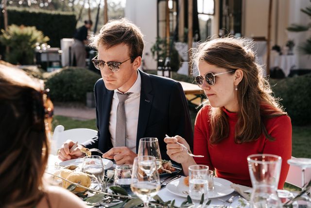 Two guests in sunglasses eat at the outdoor dinner table.