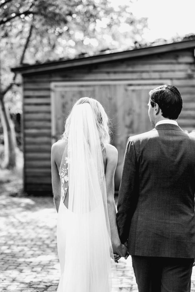 Black and white photo of a couple walking hand in hand toward a wooden doorway.