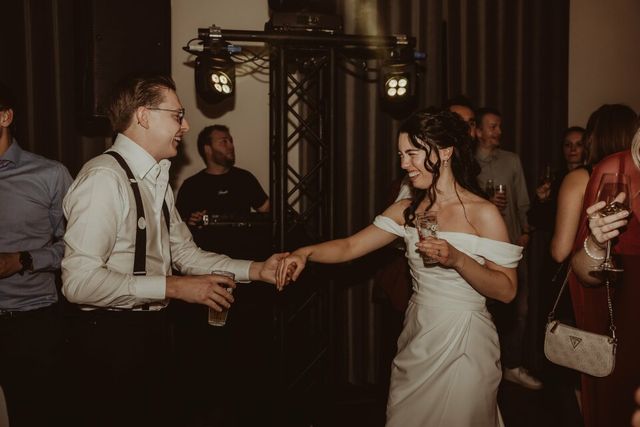 Bruidspaar danst samen tijdens de avondreceptie omringd door gasten