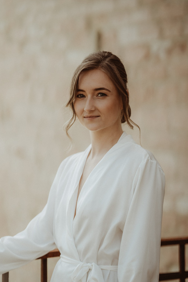 Mariée en simple peignoir blanc souriant doucement, détendue et sereine