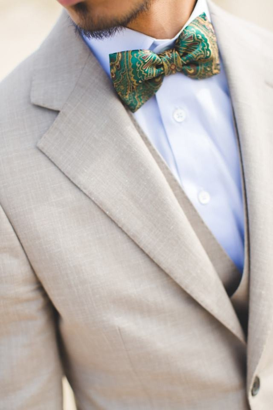 een man draagt een groene vlinderdas en een bruin pak