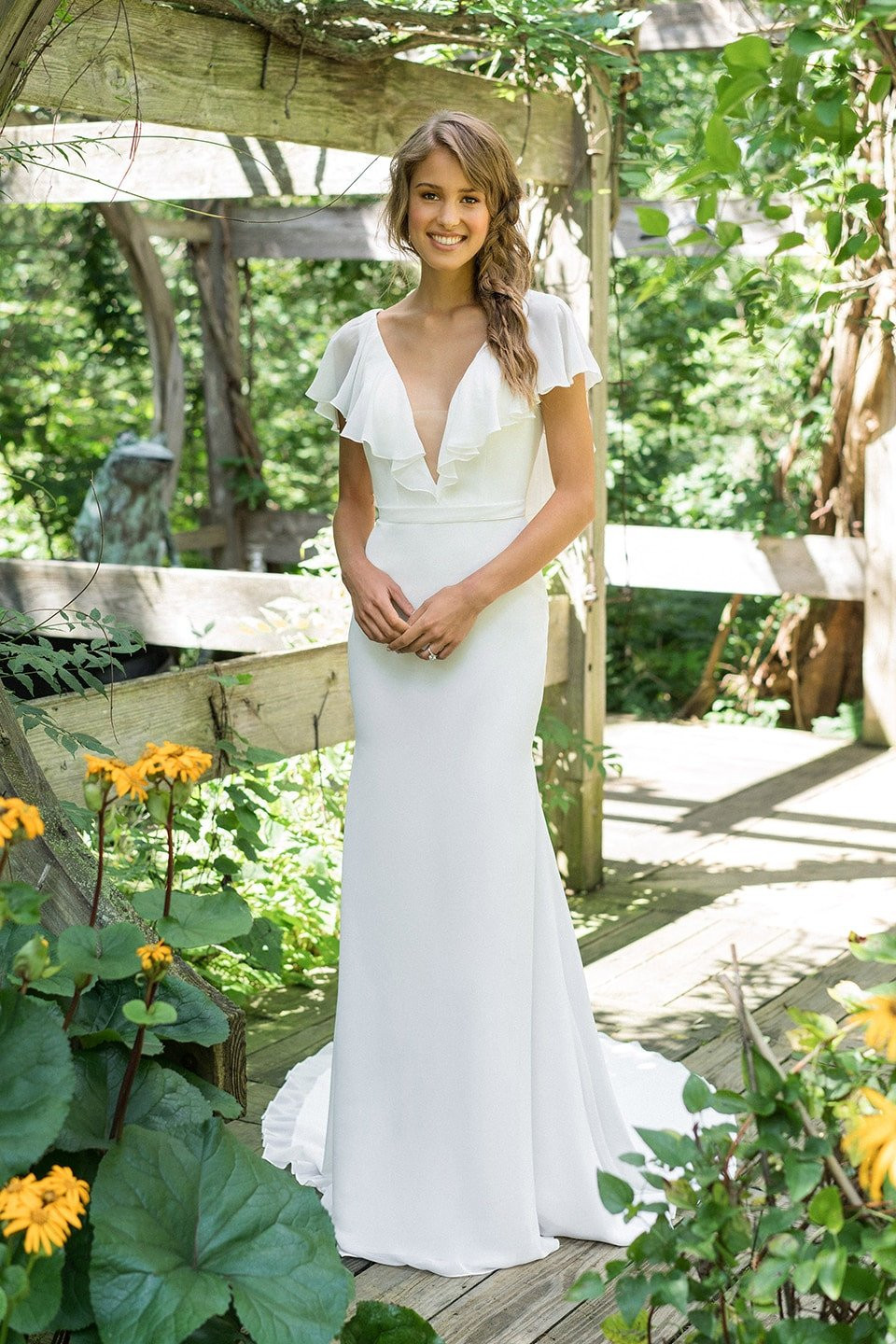 een bruid in een witte jurk die in een tuin staat