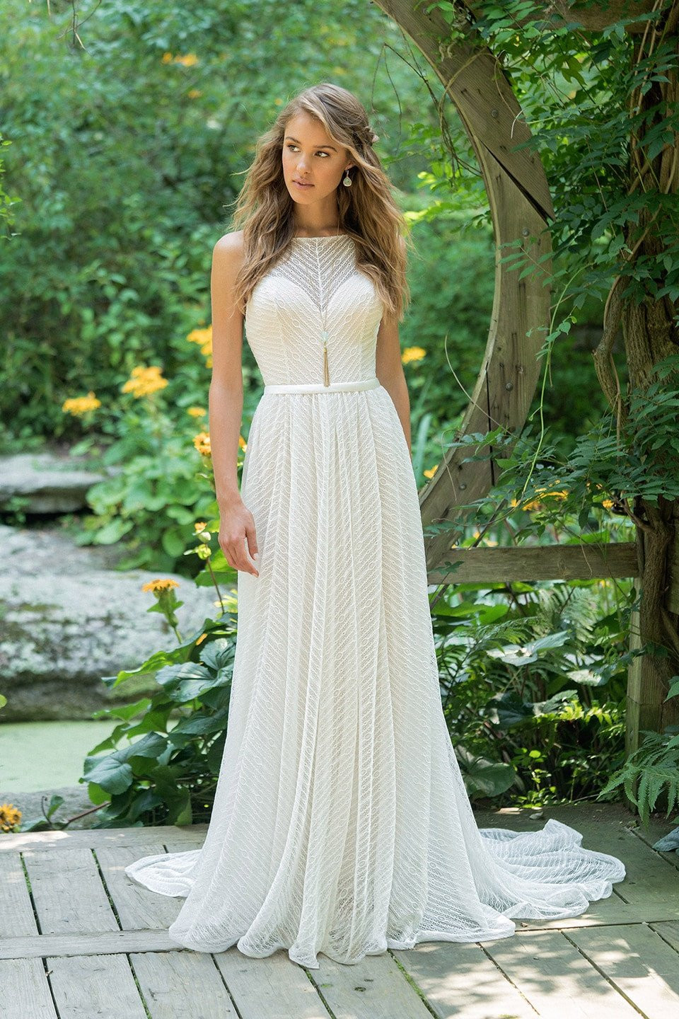 een mooie bruid in een witte trouwjurk die op een houten brug staat