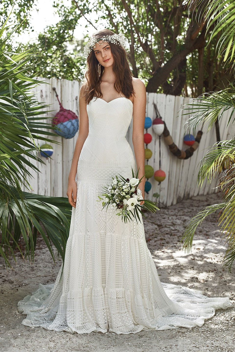 een bruid in een strapless trouwjurk staat voor een palmboom
