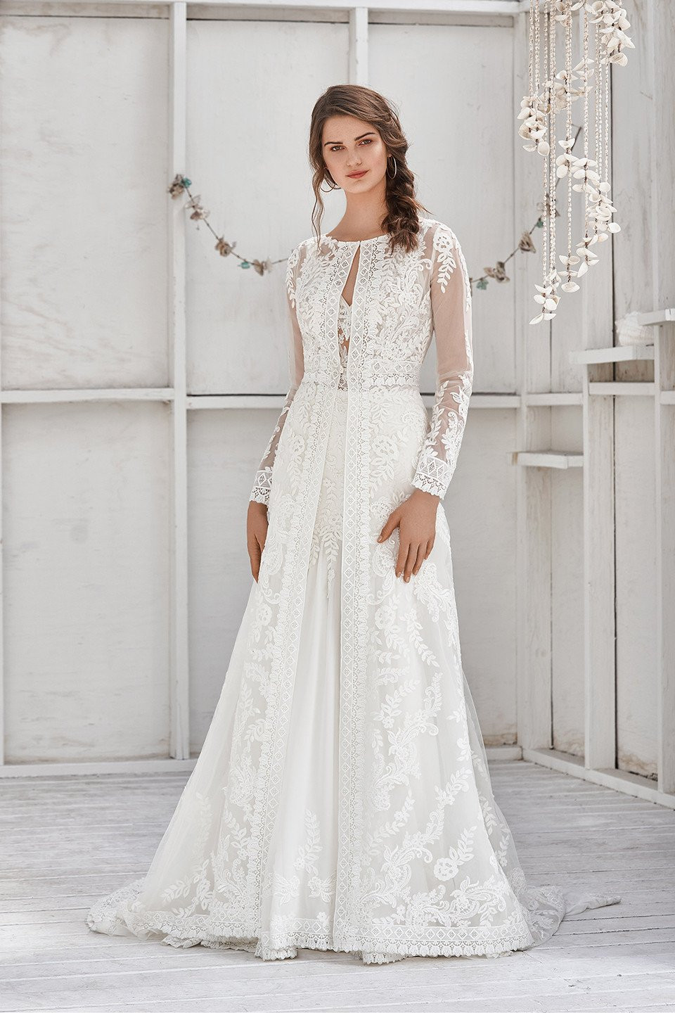 de trouwjurk is gemaakt van kant en heeft lange mouwen