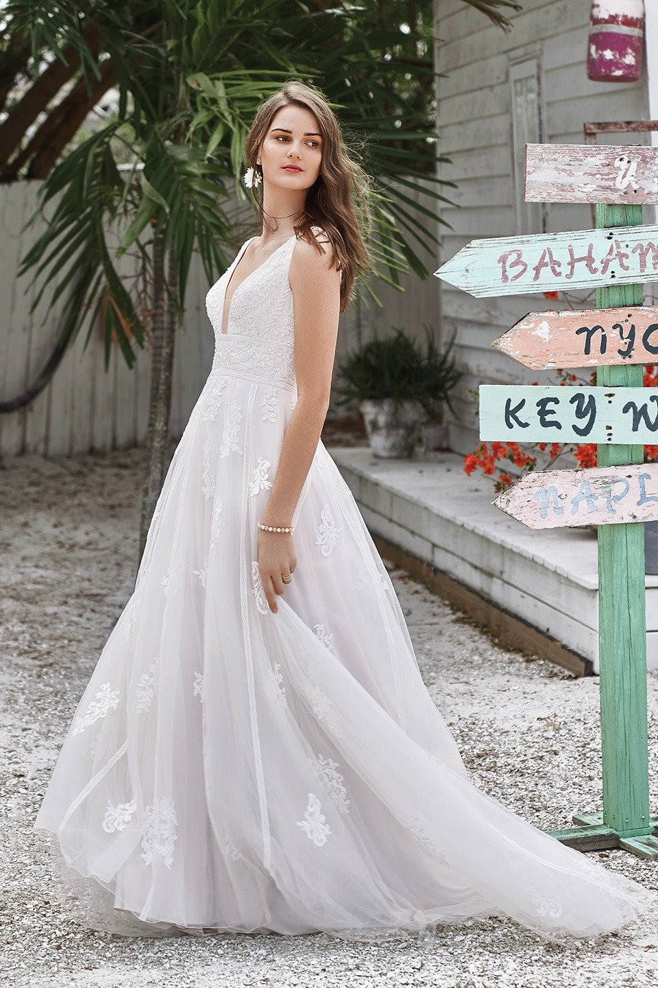 een bruid in een witte trouwjurk staande voor een bord