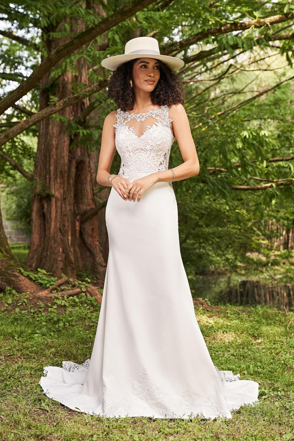een vrouw in een witte hoed en trouwjurk staat in het bos