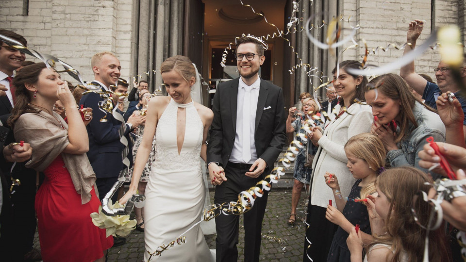 een bruid en bruidegom lopen door een menigte mensen met confetti