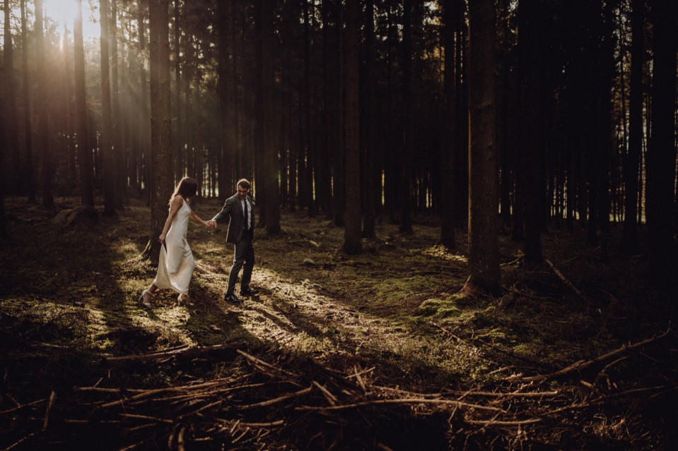 een bruid en bruidegom wandelen door het bos bij zonsondergang