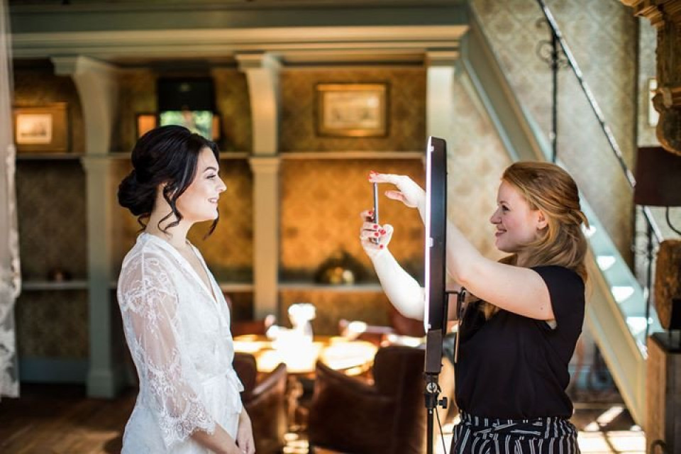 een bruid die wordt opgemaakt door haar bruidsmeisje