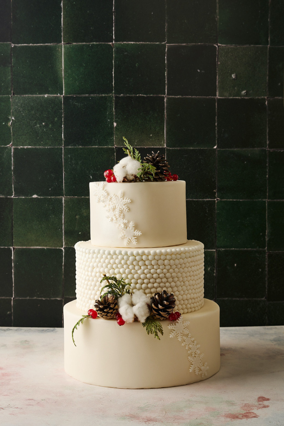 een drielaagse bruidstaart met dennenappels en bessen