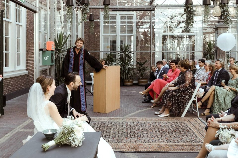 een trouwceremonie in een kas met mensen die aan tafels zitten