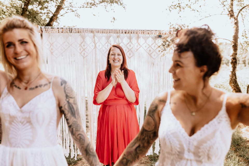 drie vrouwen in witte jurken en rode jurken lachen en glimlachen