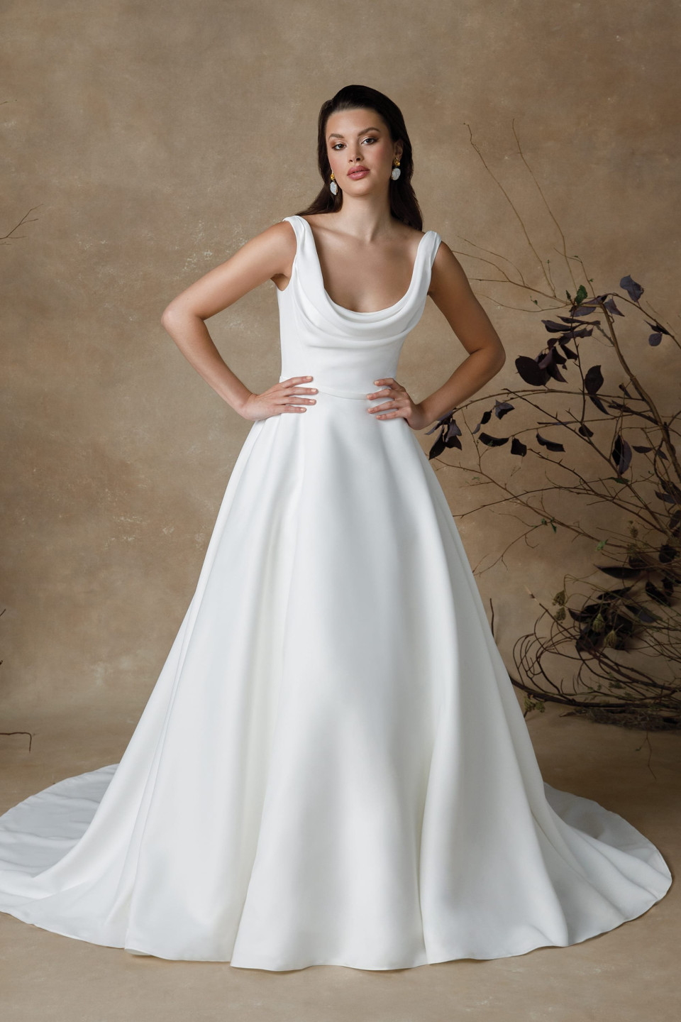 Deze elegante trouwjurk heeft een klassieke A-lijn silhouet met een moderne twist, waardoor het geschikt is voor een verscheidenheid aan lichaamstypes, met name de peer vorm, omdat het de taille accentueert en zachtjes over de heupen uitloopt. De eenvoud en gratie van het ontwerp maken het perfect voor zowel traditionele kerkelijke ceremonies als chique stedelijke bruiloften.