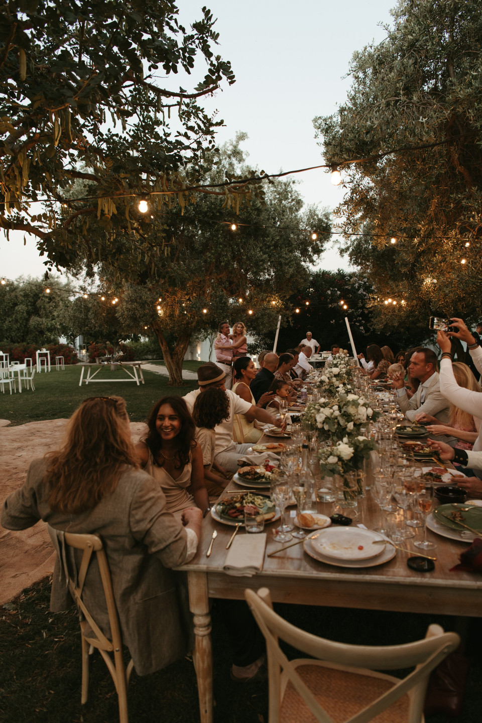 een groep mensen zit aan tafel in een tuin