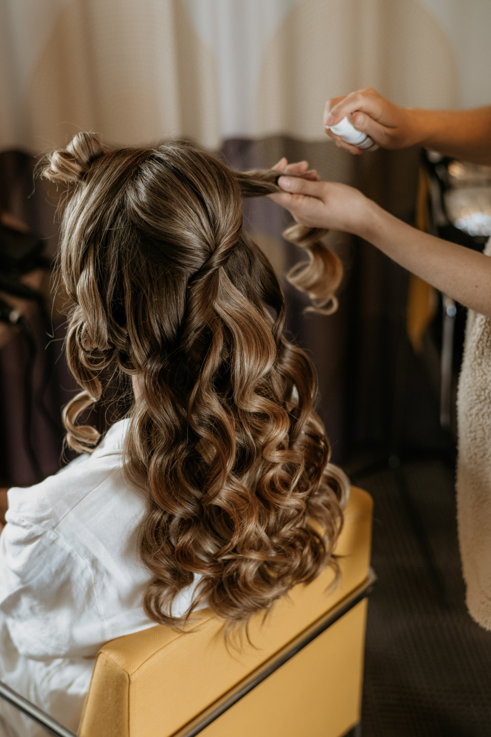 de achterkant van het hoofd van een vrouw terwijl ze haar haar laat stylen door een haarstyliste