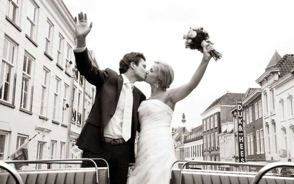 een bruid en bruidegom kussen op de achterkant van een bus