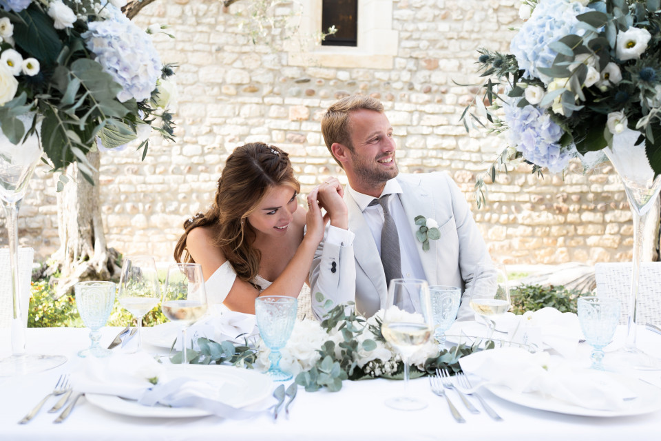een bruid en bruidegom zitten aan een tafel met bloemen