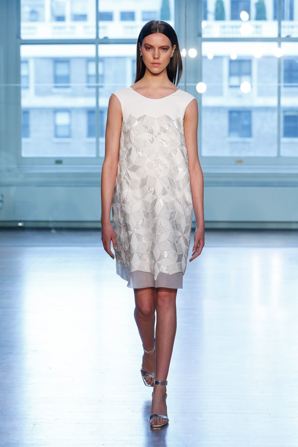 een model loopt op de catwalk in een witte jurk