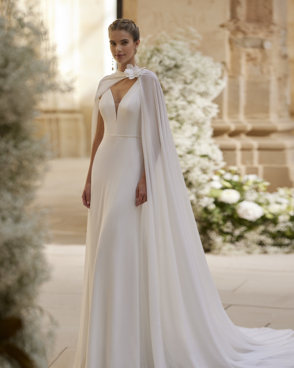 de bruid draagt een witte jurk met een cape