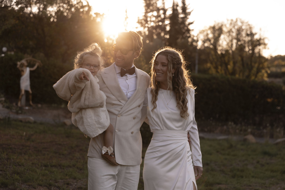 een man en vrouw in witte trouwjurk die een kind vasthouden