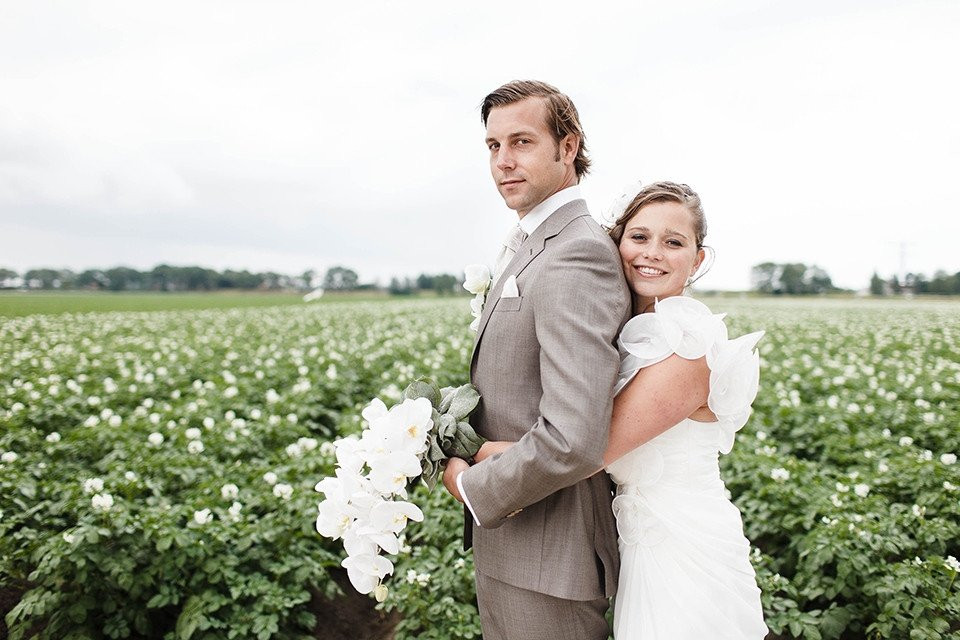 een bruid en bruidegom staan in een veld van witte bloemen