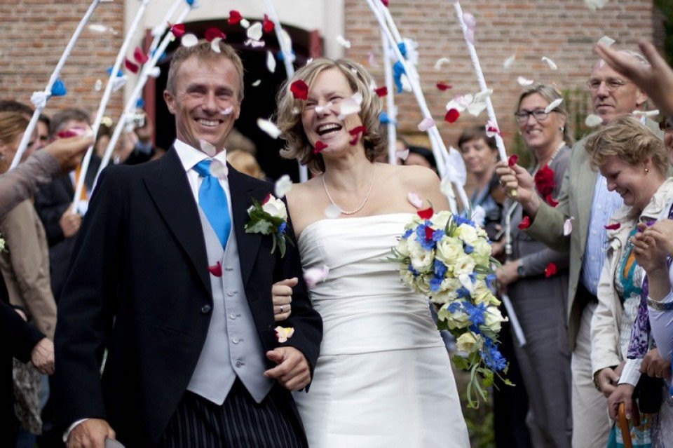 een pasgetrouwd stel loopt het gangpad af met confetti