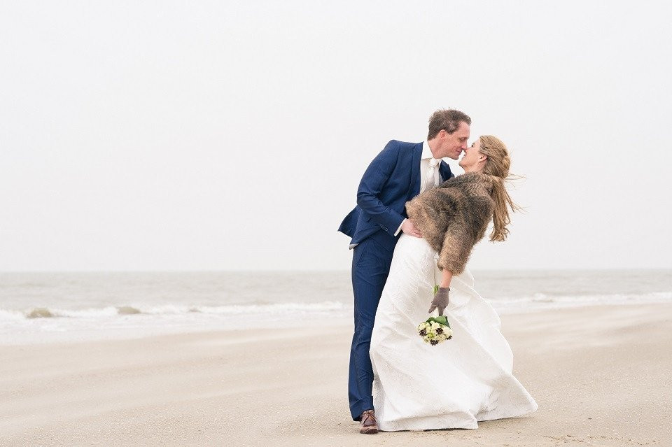 een bruid en bruidegom kussen op het strand