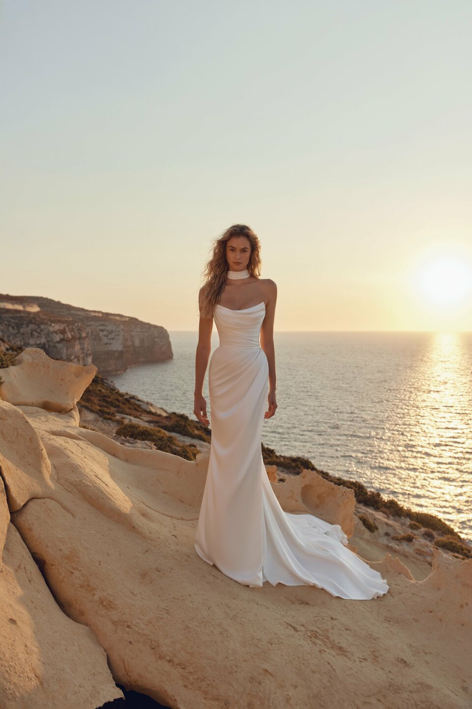 een vrouw in een trouwjurk die op een rots staat