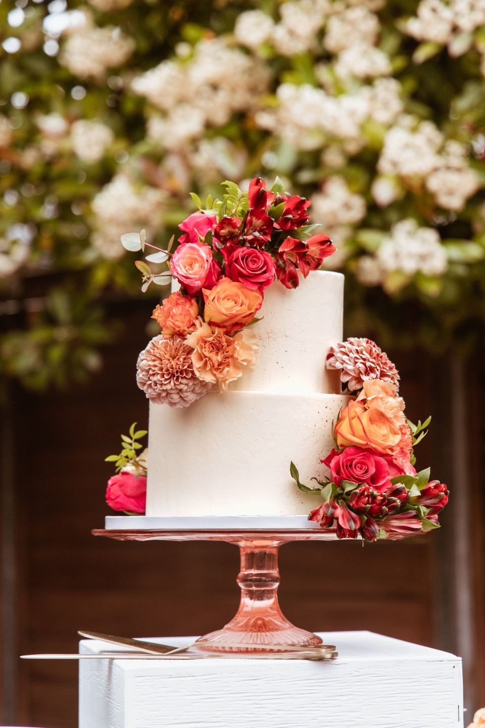 een close-up van een bruidstaart met bloemen op de bovenkant en een mes aan de zijkant van de taart