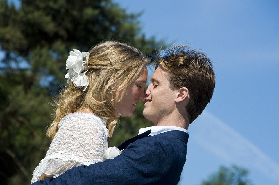 een jonge man en vrouw kussen voor een boom
