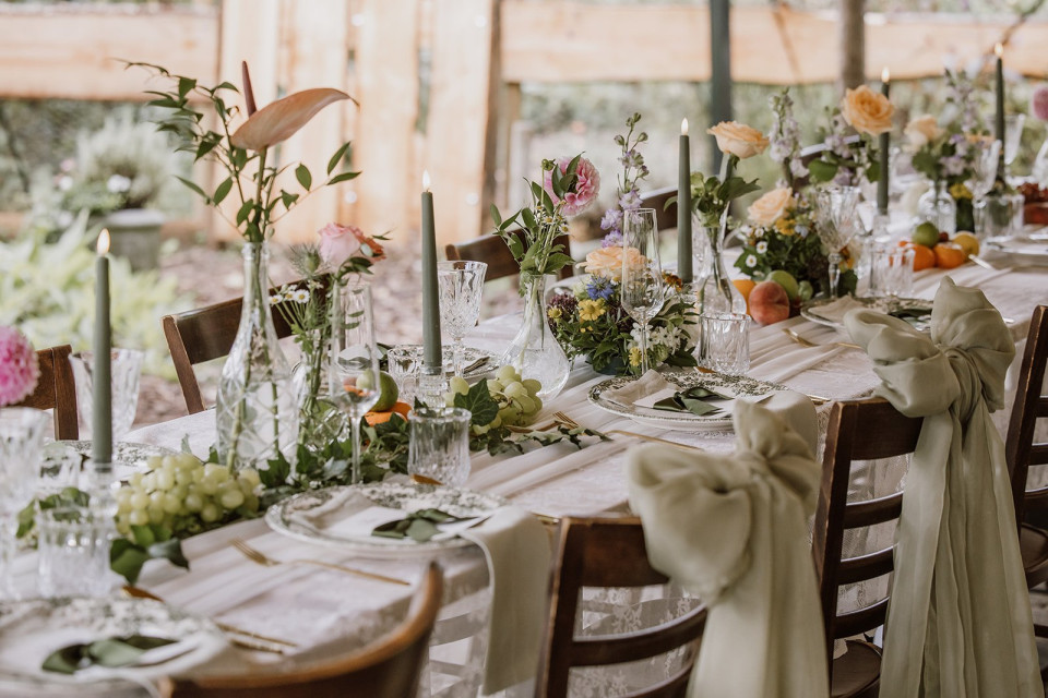 een lange tafel opgezet met bloemen en kaarsen