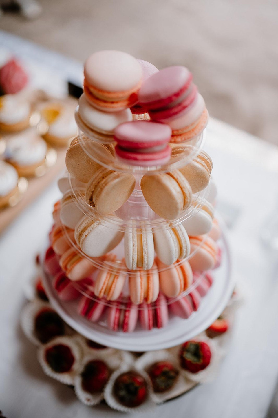 een stapel macarons op elkaar met aardbeien op de bodem van de etagère