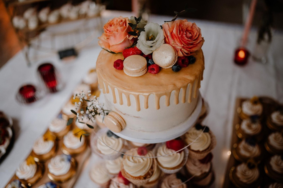 een taart met bloemen erop op een tafel met cupcakes en desserts op de achtergrond