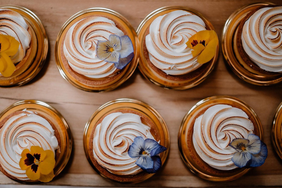 een verscheidenheid aan cupcakes met glazuur en bloemen erop in een kartonnen doos op een tafel
