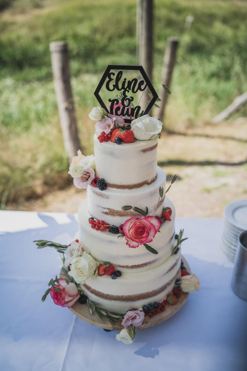 een close-up van een bruidstaart met bloemen en een bord dat 'elope team' op de bovenkant zegt