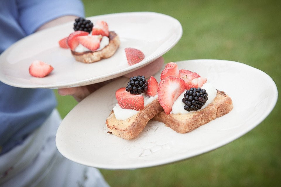 een persoon die twee borden vasthoudt met toast en bessen