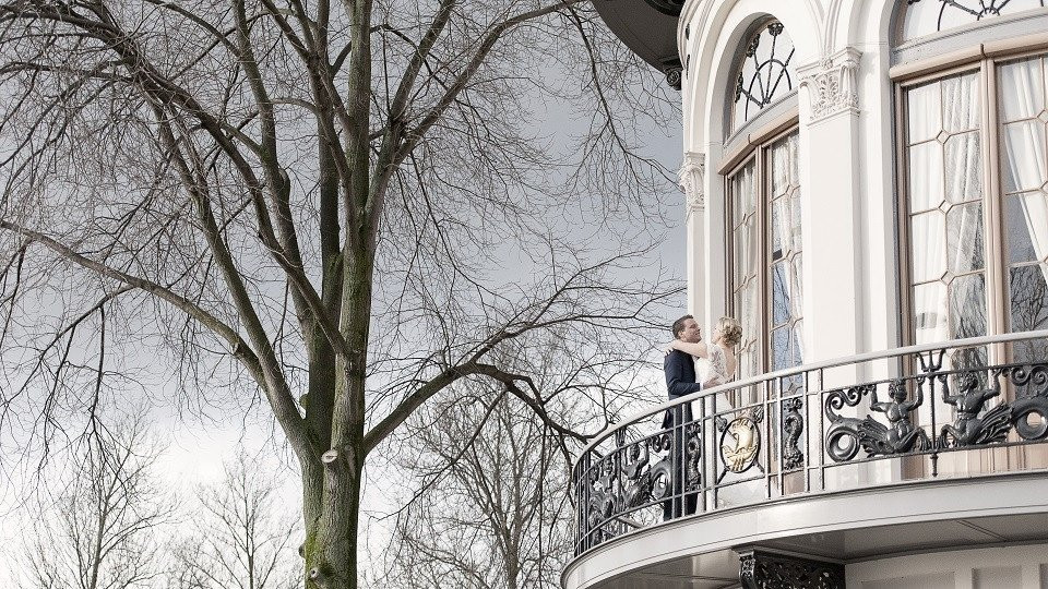 een vrouw staat op het balkon van een groot huis