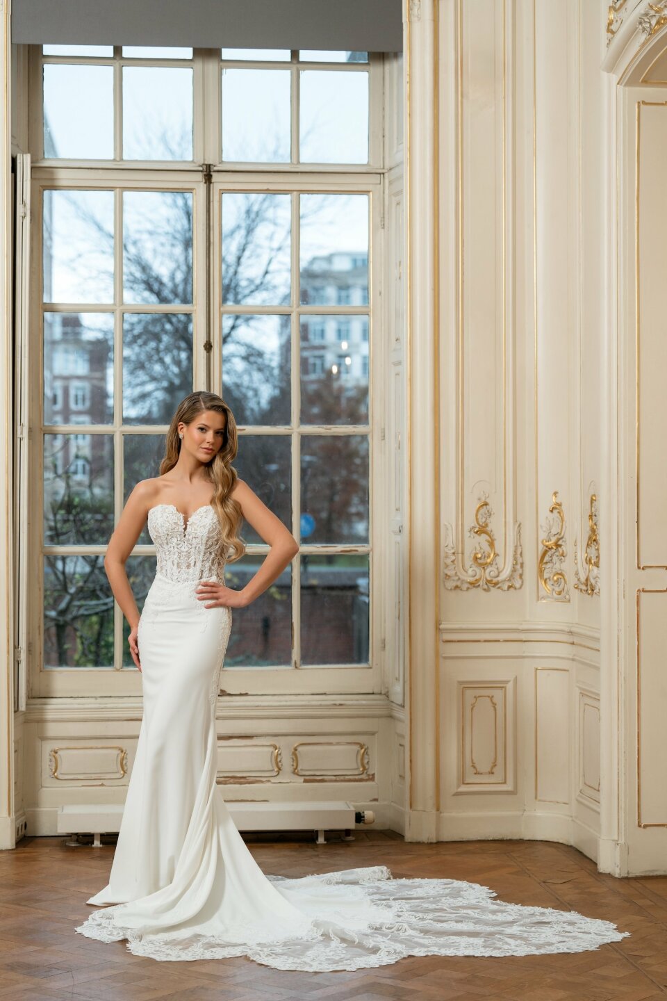 een vrouw in een trouwjurk die voor een raam staat