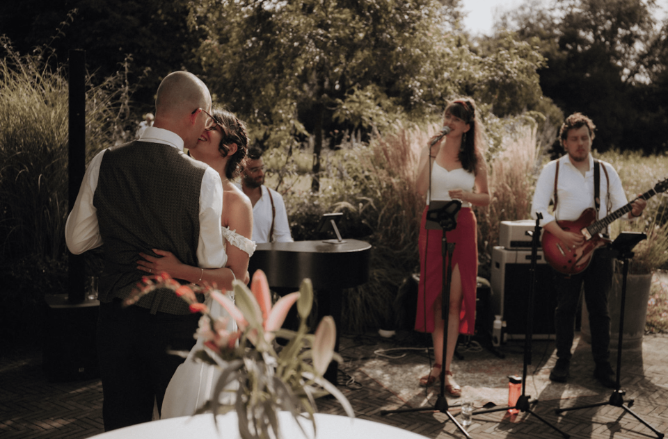een man en een vrouw die voor een groep mensen staan met gitaren en een man die gitaar speelt