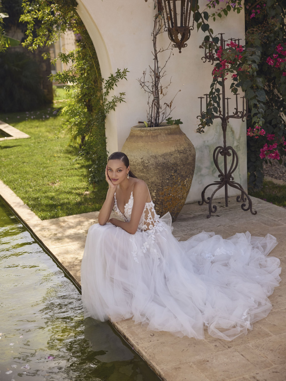 een vrouw in een trouwjurk die op de rand van een zwembad zit